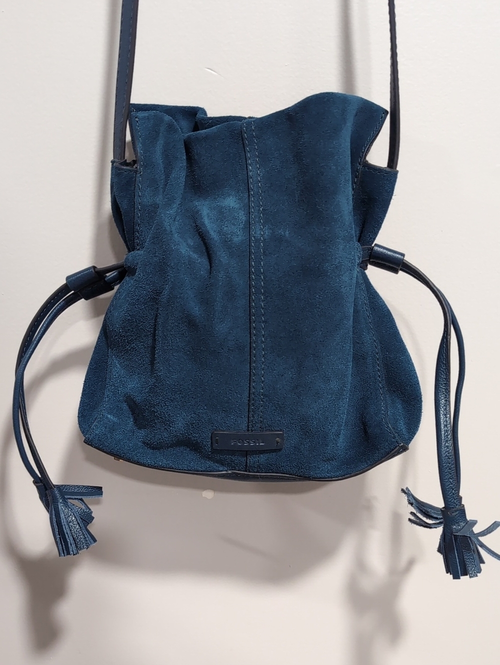 Fossil Blue Suede Bucket Bag with Drawstring Closure And Tassel Details.